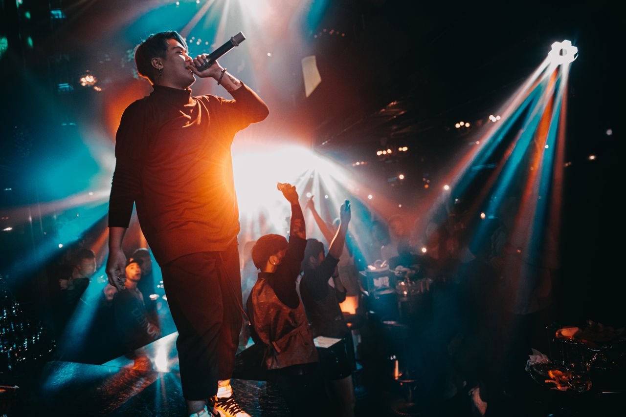 Energetic live performance with a singing artist in a vibrant nightclub atmosphere.